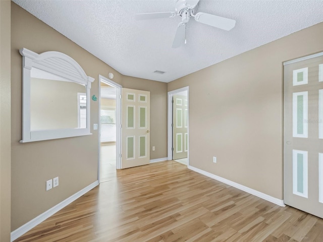 empty room featuring a textured ceiling, light hardwood / wood-style floors, and ceiling fan