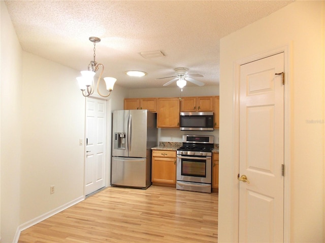 kitchen with baseboards, decorative light fixtures, stainless steel appliances, a textured ceiling, and light wood-type flooring