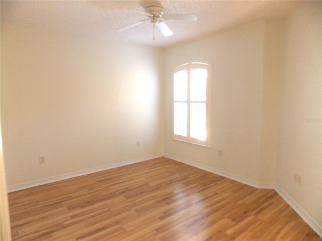 empty room with baseboards, ceiling fan, and light wood finished floors