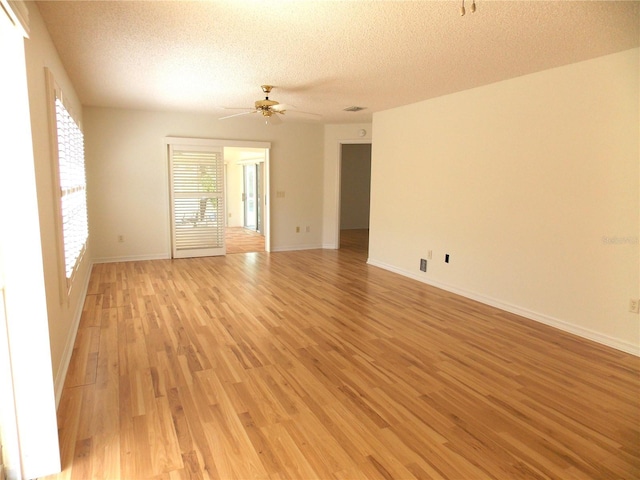 spare room with light wood-type flooring, ceiling fan, a textured ceiling, and baseboards