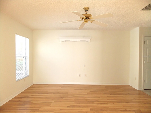 unfurnished room with light wood finished floors, baseboards, visible vents, ceiling fan, and a textured ceiling