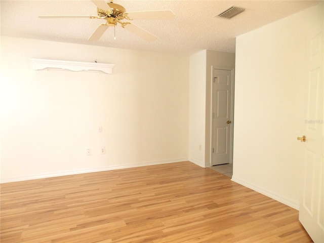 spare room featuring a textured ceiling, a ceiling fan, baseboards, visible vents, and light wood-style floors