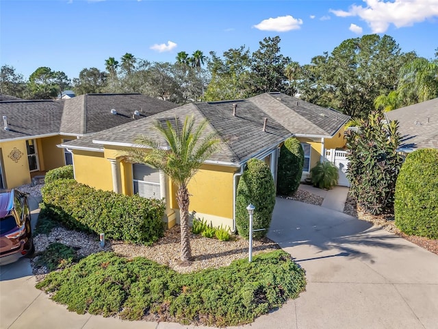 ranch-style home featuring driveway, roof with shingles, and stucco siding