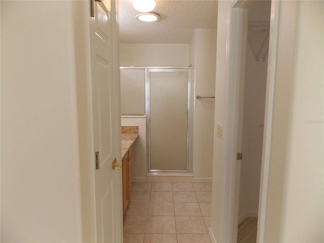 full bathroom with a textured ceiling, tile patterned flooring, vanity, a closet, and a stall shower