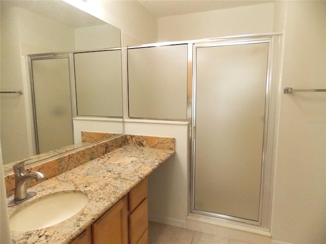 bathroom featuring tile patterned flooring, a shower stall, and vanity