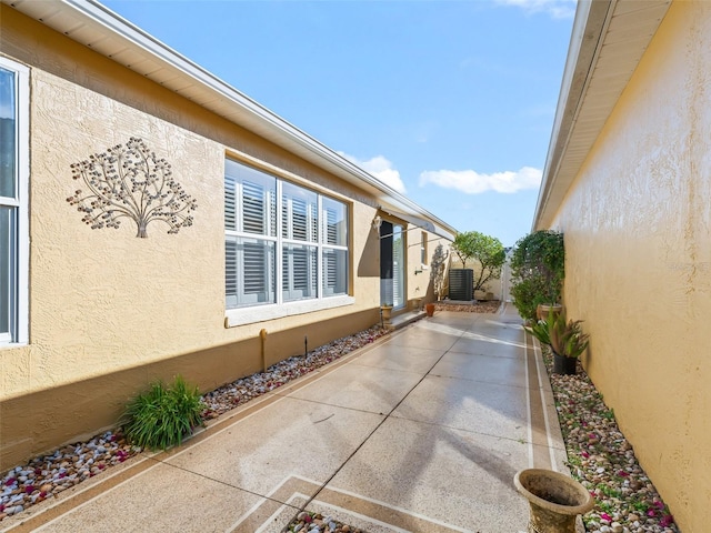 view of side of home with central AC unit, a patio, and stucco siding