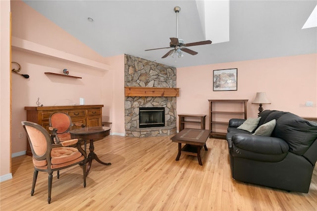 living room featuring a fireplace, light wood-type flooring, ceiling fan, and lofted ceiling