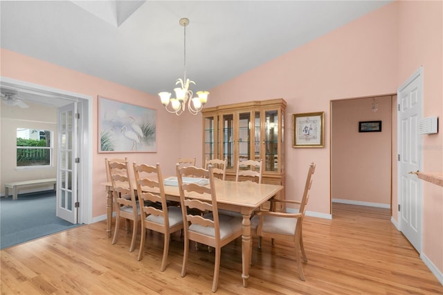 dining space featuring light hardwood / wood-style flooring, ceiling fan with notable chandelier, and lofted ceiling