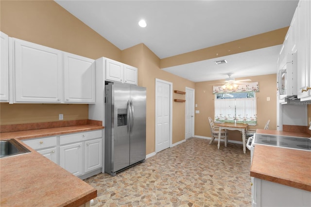 kitchen with ceiling fan, stainless steel fridge, white cabinetry, and vaulted ceiling