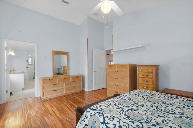 bedroom featuring connected bathroom, ceiling fan, a towering ceiling, and light hardwood / wood-style floors