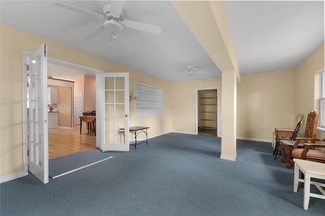 carpeted living room with ceiling fan, built in shelves, and french doors