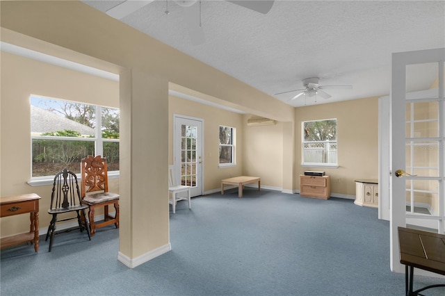 living area featuring an AC wall unit, ceiling fan, carpet floors, and a textured ceiling