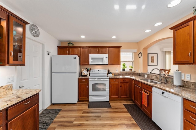 kitchen featuring light stone counters, sink, white appliances, and light hardwood / wood-style flooring