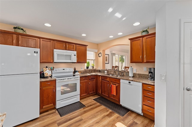 kitchen featuring light wood-type flooring, white appliances, light stone countertops, and sink