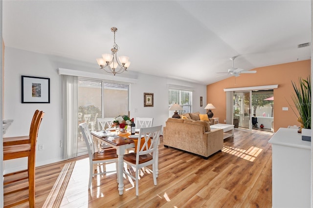 dining room featuring ceiling fan with notable chandelier, light hardwood / wood-style floors, and vaulted ceiling