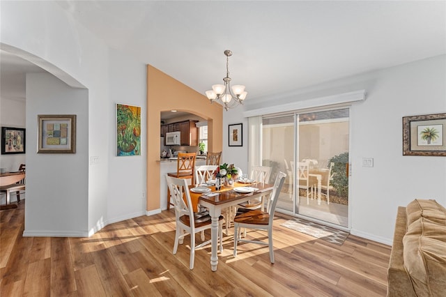 dining space featuring light hardwood / wood-style floors, lofted ceiling, and a chandelier