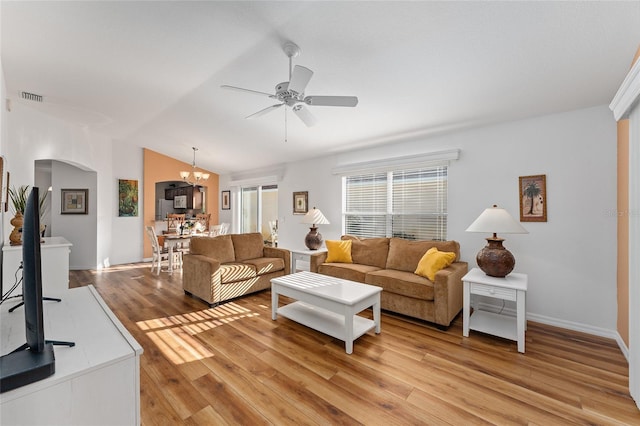 living room featuring vaulted ceiling, ceiling fan with notable chandelier, and light wood-type flooring