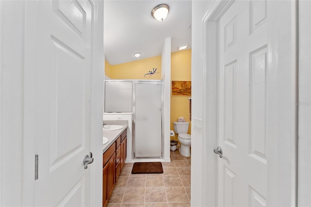 bathroom with vanity, vaulted ceiling, tile patterned flooring, toilet, and an enclosed shower