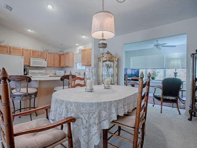 dining space with lofted ceiling, light carpet, and ceiling fan