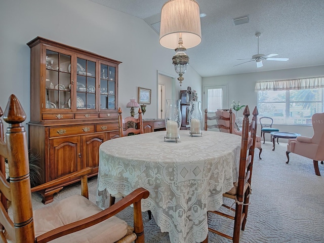 carpeted dining space featuring ceiling fan, vaulted ceiling, and a textured ceiling