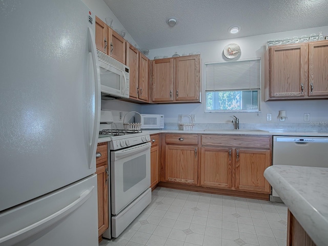 kitchen with sink, white appliances, and a textured ceiling