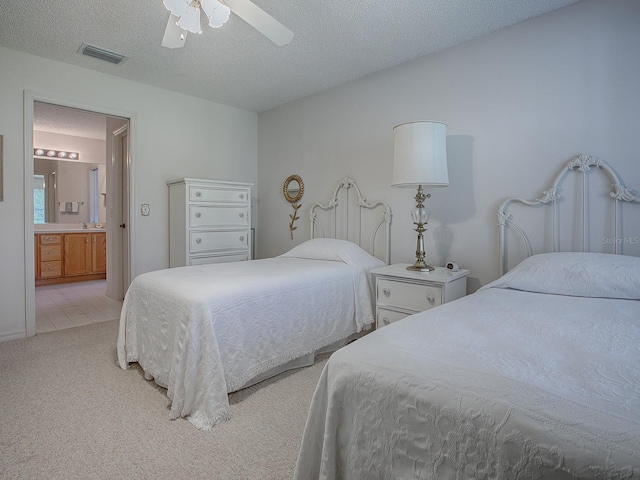 carpeted bedroom with ensuite bathroom, a textured ceiling, and ceiling fan