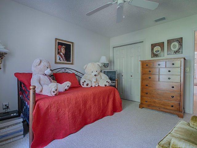 carpeted bedroom featuring a closet, ceiling fan, and a textured ceiling