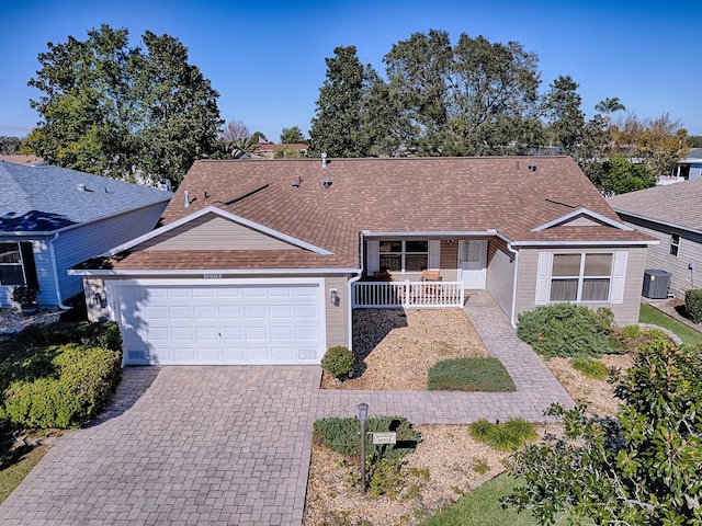 ranch-style home featuring central AC, covered porch, and a garage