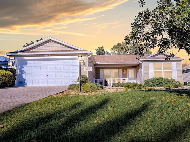 ranch-style home featuring a garage, covered porch, and a yard