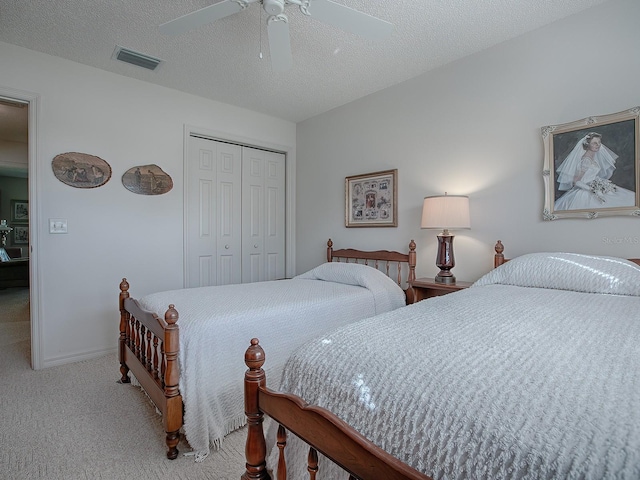 bedroom with ceiling fan, light colored carpet, a closet, and a textured ceiling