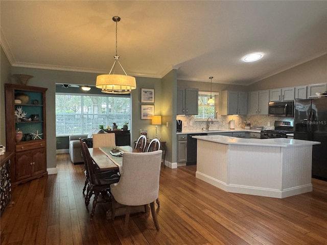 dining area with sink, wood-type flooring, ornamental molding, and vaulted ceiling