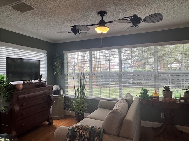 living room with ceiling fan, hardwood / wood-style floors, ornamental molding, and a textured ceiling