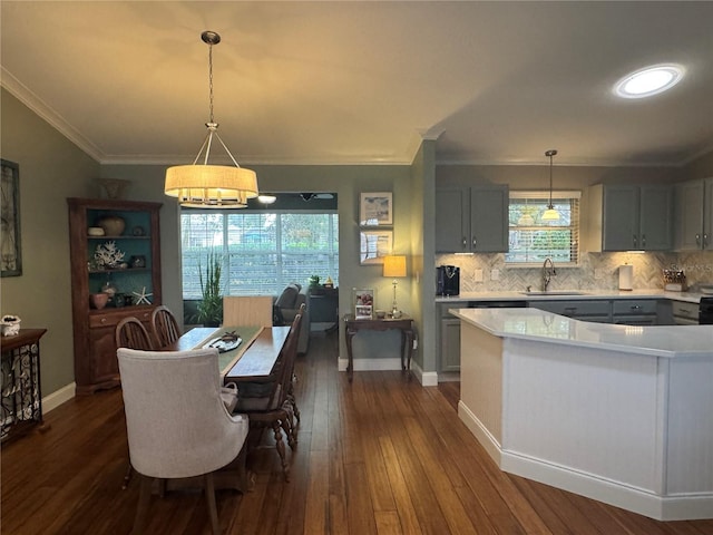 kitchen with pendant lighting, sink, dark hardwood / wood-style floors, ornamental molding, and gray cabinetry