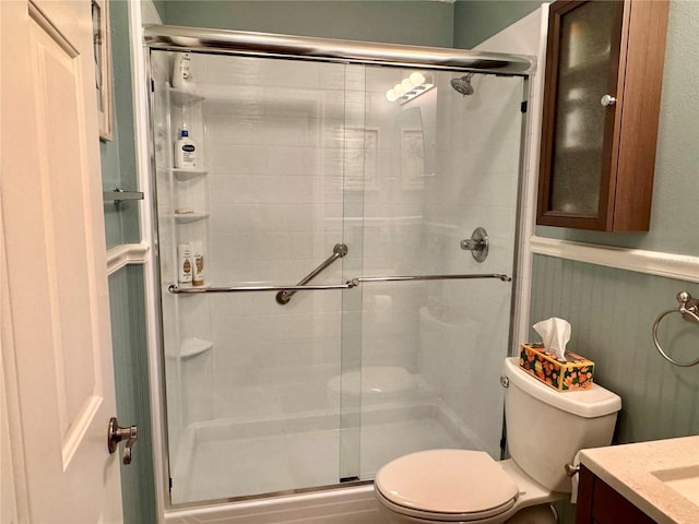 bathroom with a shower with door, toilet, and vanity