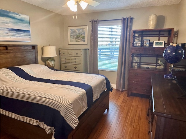 bedroom with ceiling fan, a textured ceiling, and hardwood / wood-style flooring