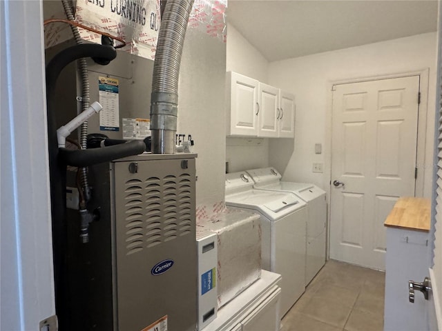 laundry room featuring cabinets, light tile patterned floors, and washing machine and dryer