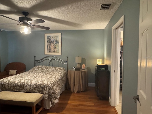 bedroom featuring ceiling fan, hardwood / wood-style floors, and a textured ceiling