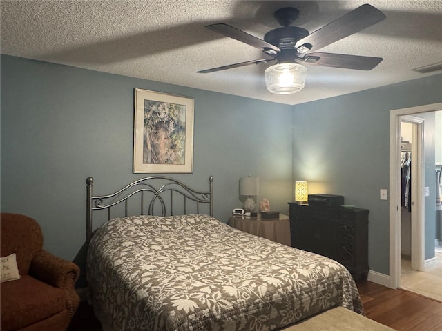 bedroom with ceiling fan, wood-type flooring, and a textured ceiling