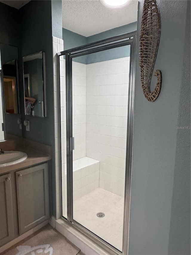 bathroom with a textured ceiling, an enclosed shower, and vanity