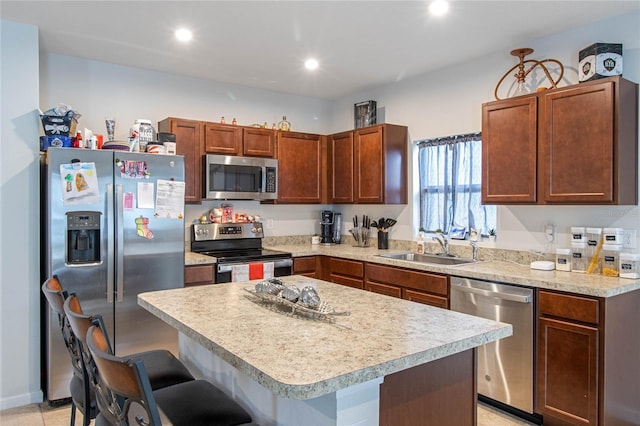 kitchen featuring sink, light tile patterned floors, a kitchen breakfast bar, a kitchen island, and appliances with stainless steel finishes