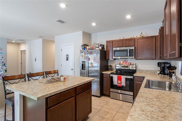 kitchen featuring a breakfast bar, a center island, stainless steel appliances, and sink