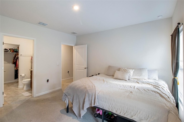 carpeted bedroom featuring connected bathroom, a walk in closet, and a closet