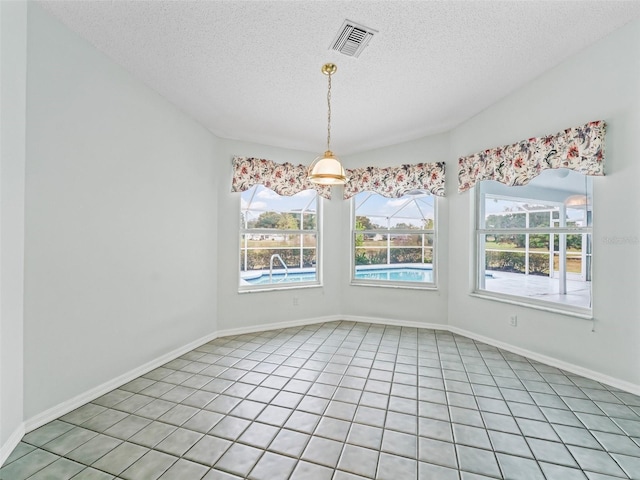 unfurnished dining area with light tile patterned floors, a textured ceiling, and vaulted ceiling