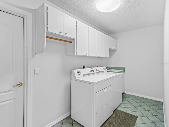 laundry area featuring cabinets, light tile patterned floors, washing machine and dryer, and a textured ceiling