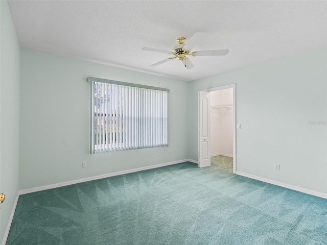 carpeted spare room featuring a textured ceiling and ceiling fan