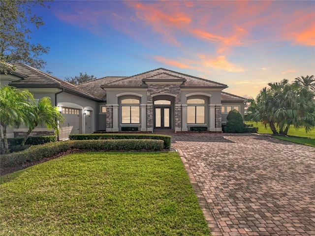 mediterranean / spanish home featuring a garage, a yard, and french doors