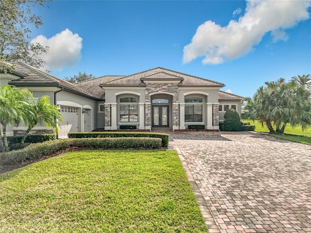 view of front facade with a garage, french doors, and a front lawn