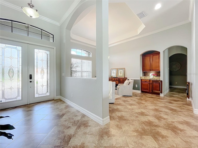 entryway with plenty of natural light, ornamental molding, and light tile patterned flooring