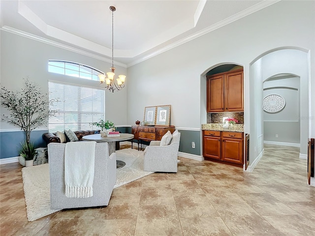 dining room featuring a chandelier, a raised ceiling, and ornamental molding