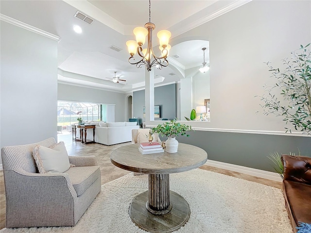 living room with a tray ceiling, ceiling fan with notable chandelier, and ornamental molding